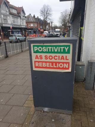 Positivity as social rebellion - a moribund statement on a dark and shuttered high street in Birmingham, England.