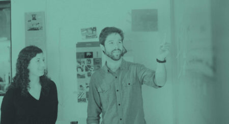 Two people discussing writing on a whiteboard