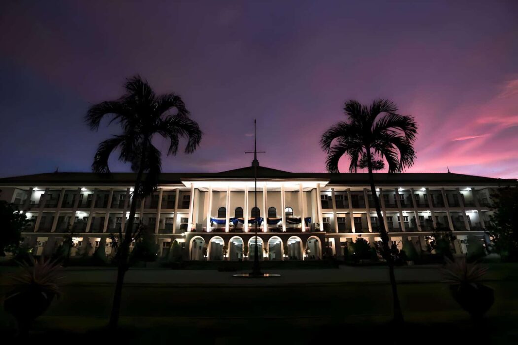 UGM campus building lit up at night with pink sky