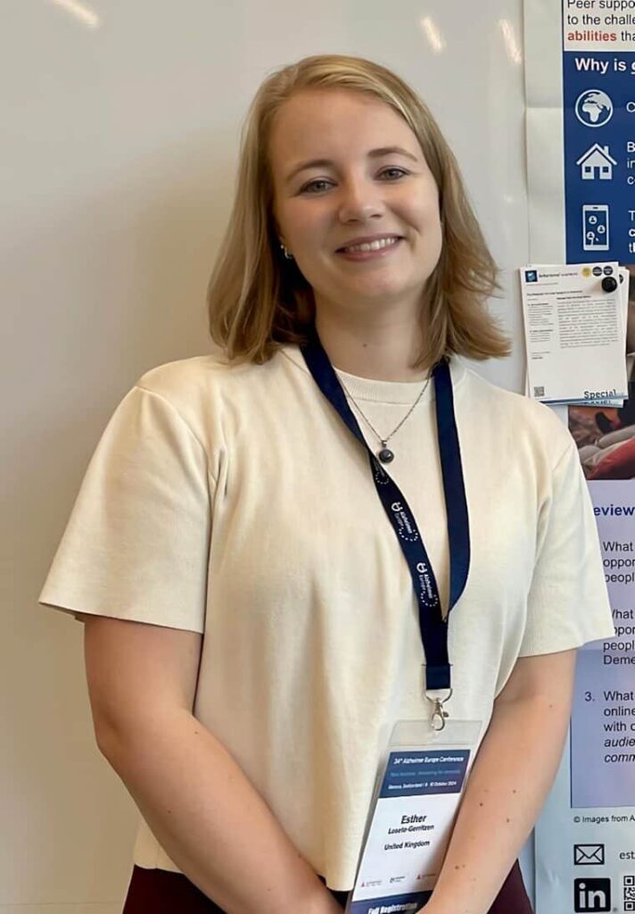 Photo of Esther facing and smiling at the camera wearing a lanyard and white top