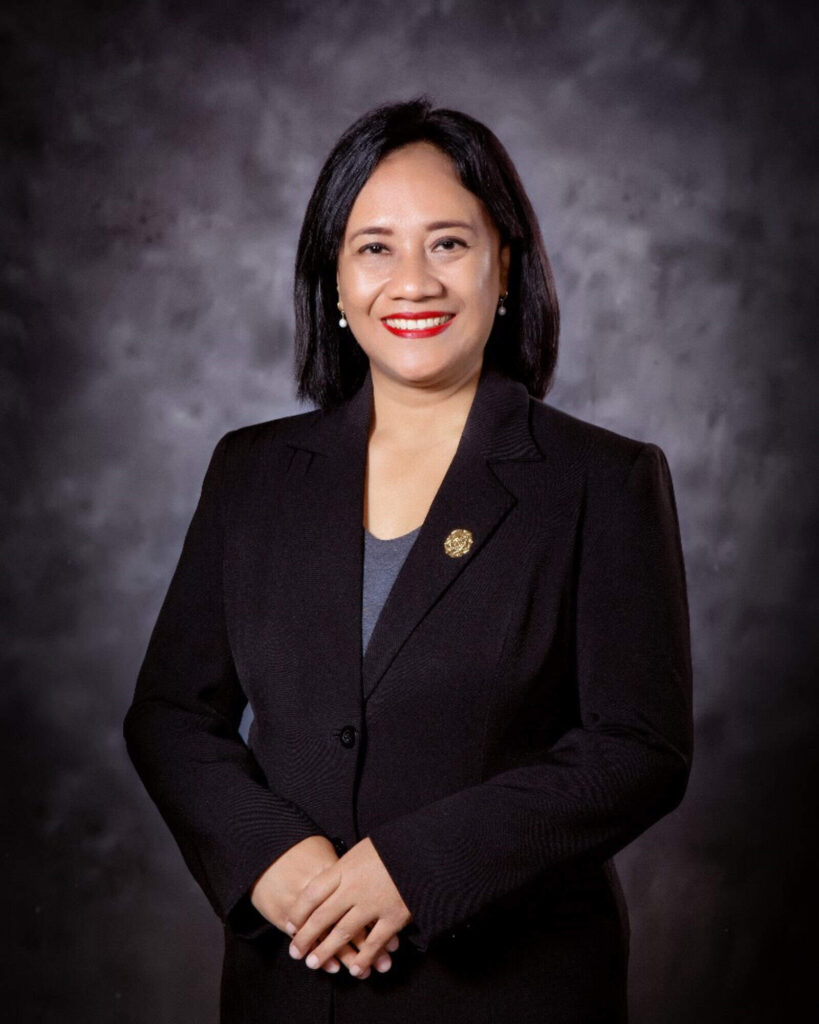 Photo of Prof Wening stood in from of a professional background facing and smiling to the camera with hands clasped